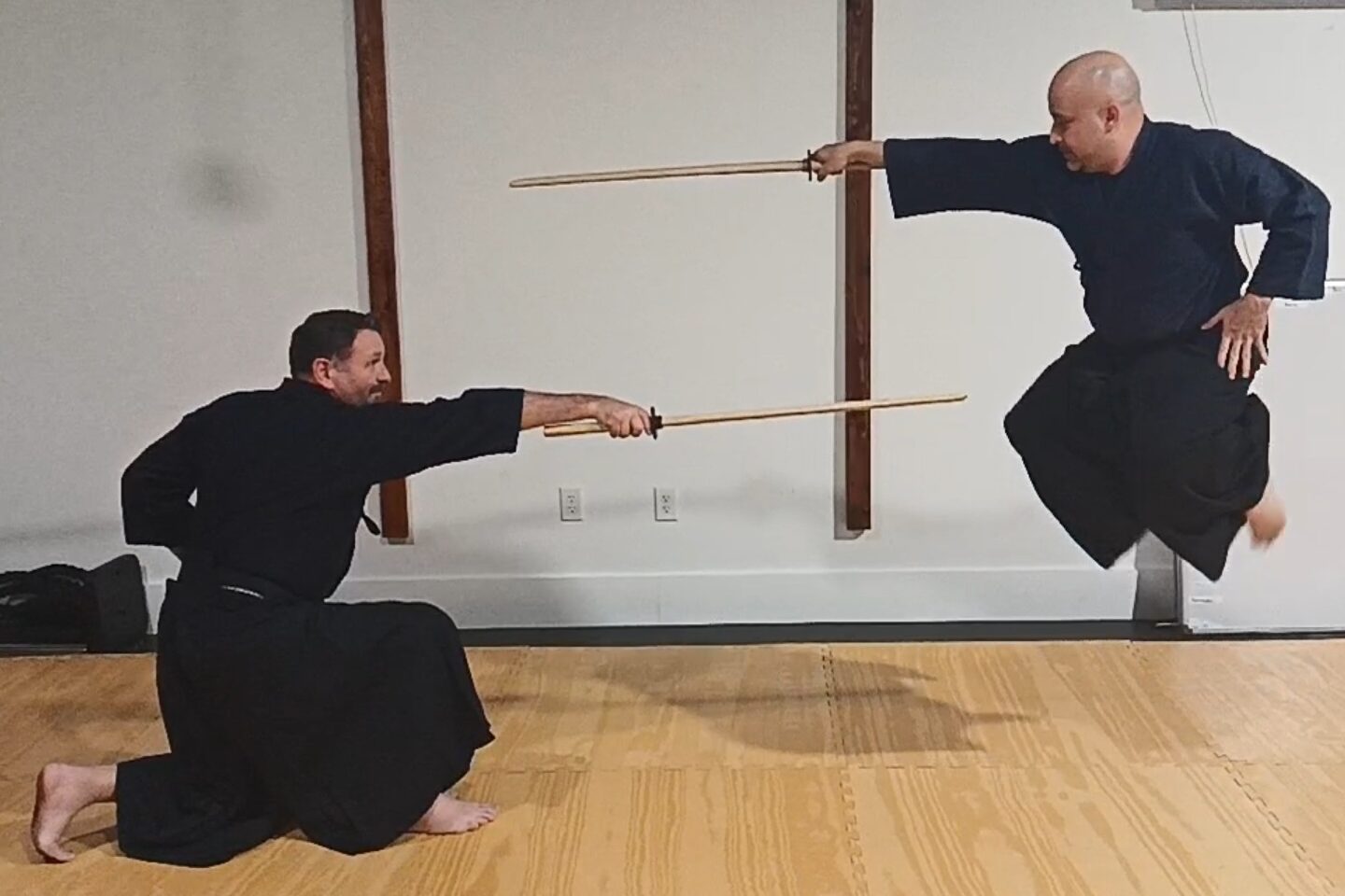 Two swordsmen dressed in blue and black cutting at each other